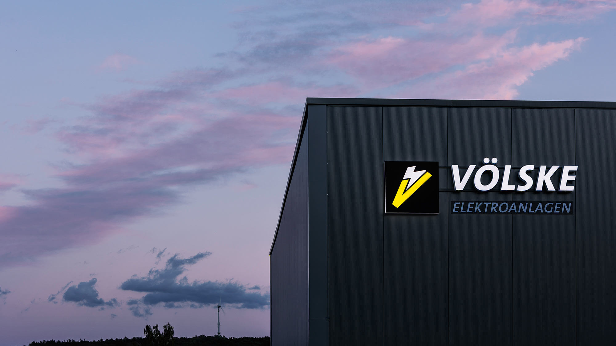 Leuchtreklame an Firmengebäude beim Sonnenuntergang
