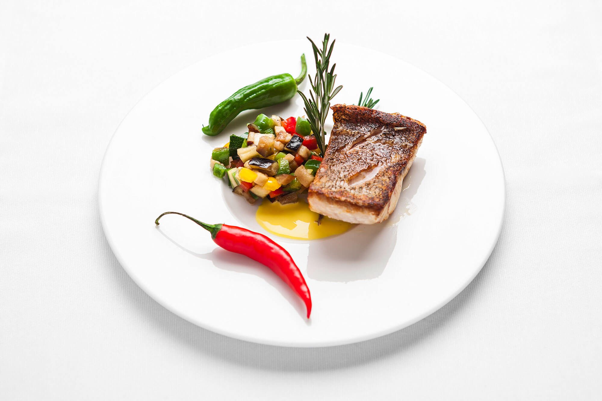 Fisch und Gemüse mit Soße auf weißem Teller