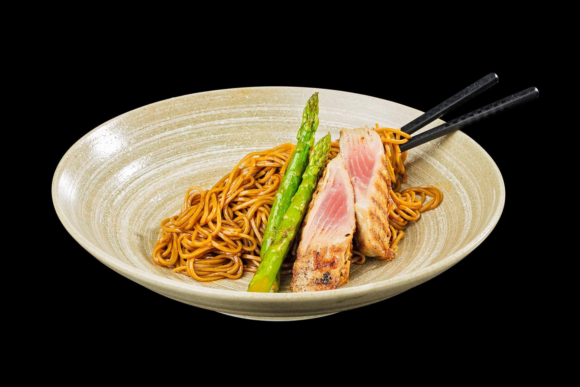 Pasta mit Thunfisch und Spargel vor schwarzem Hintergrund