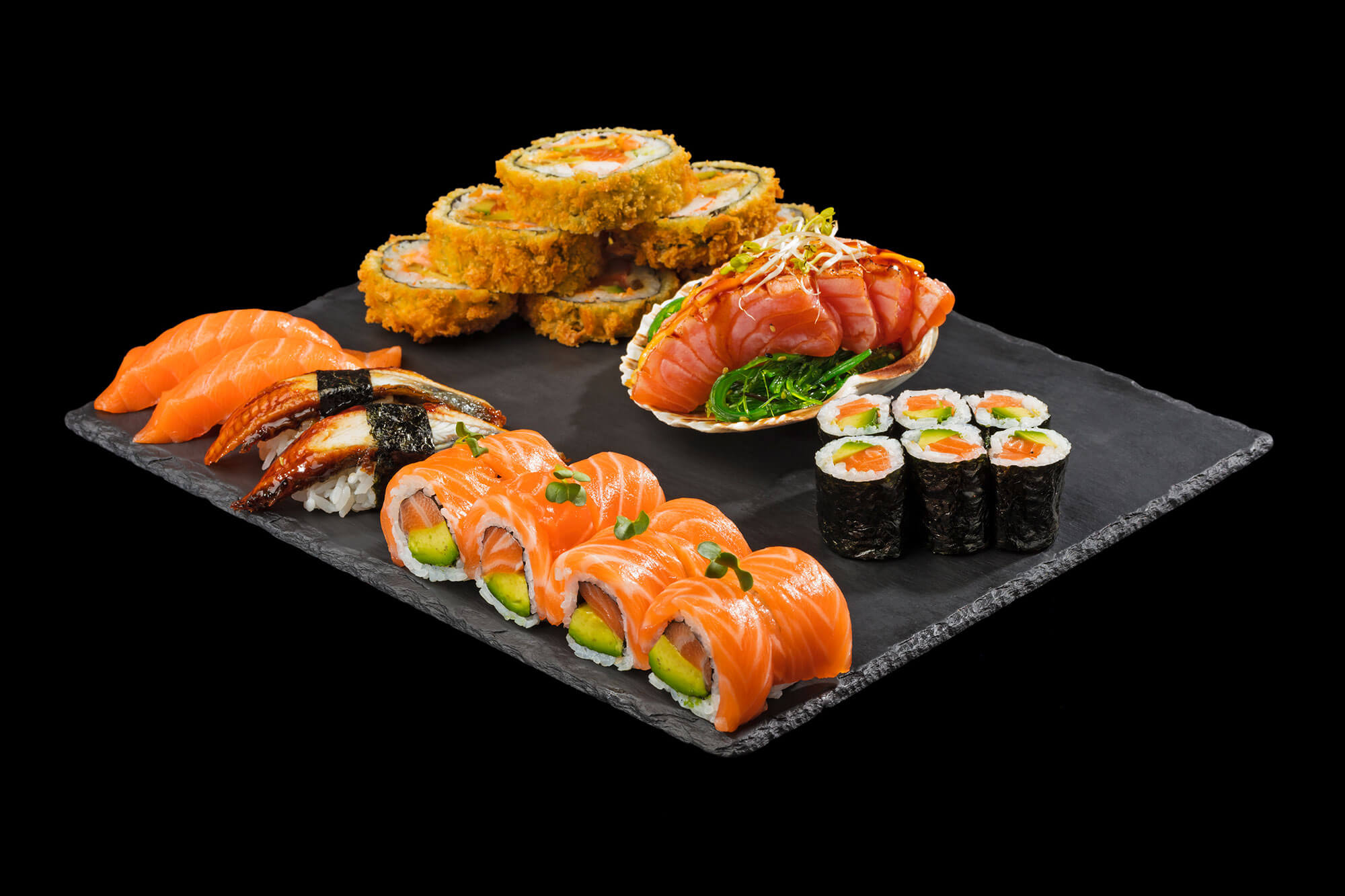 Sushi Platte auf Schieferplatte vor schwarzem Hintergrund