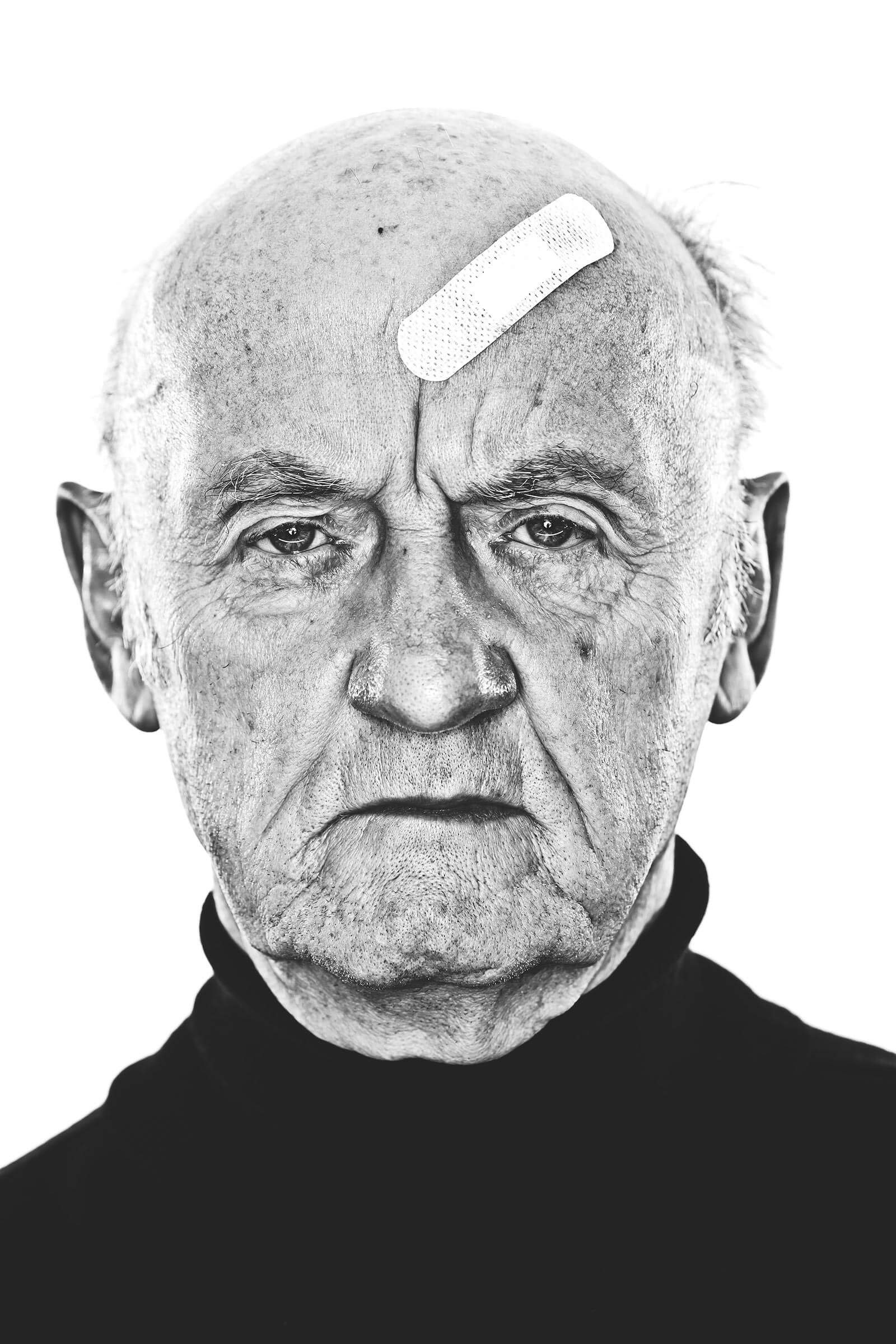 Portrait alter Mann mit Pflaster vor weißem Hintergrund