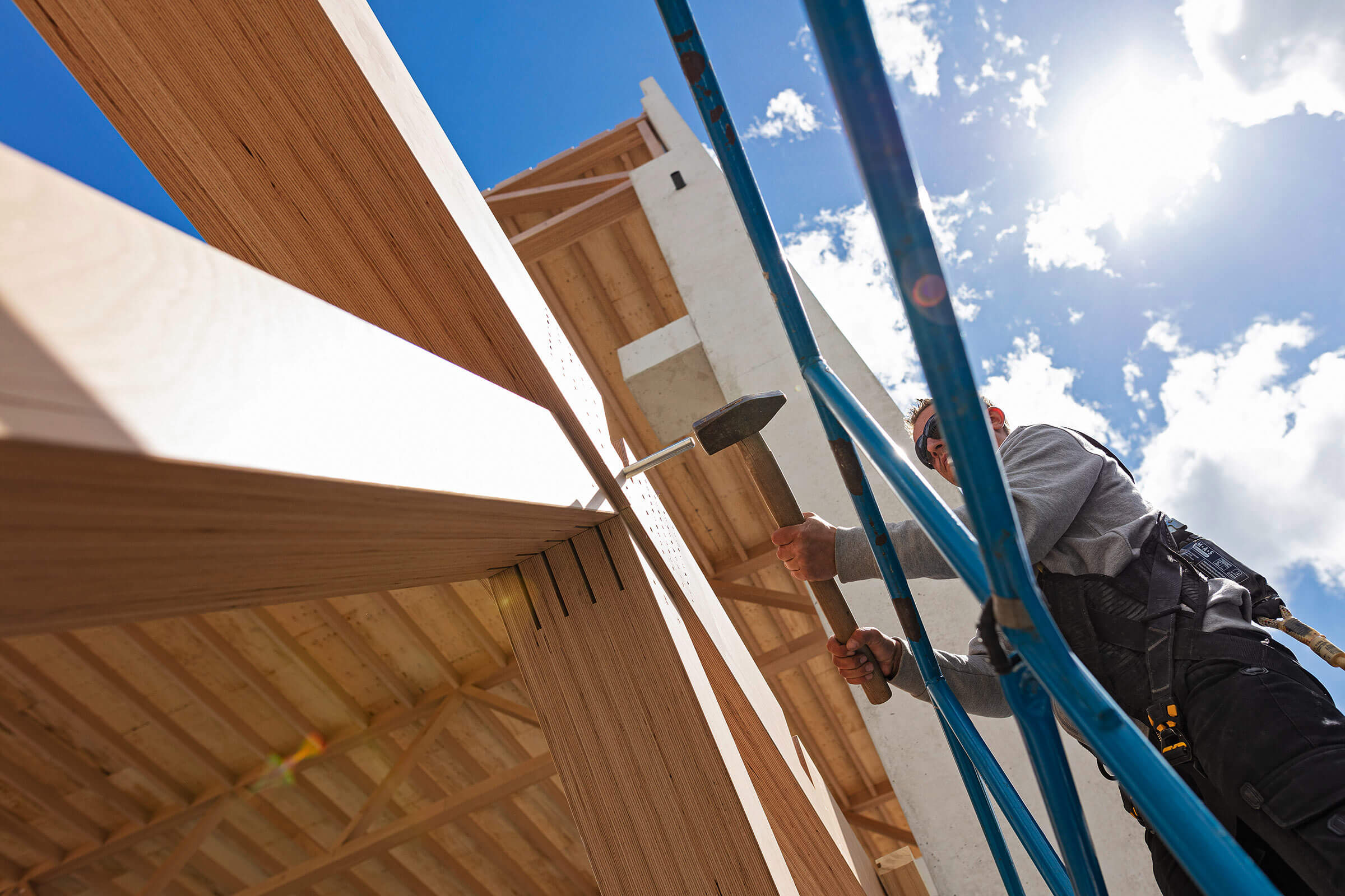 Mann verbindet Holzelemente auf einer Baustelle im Gegenlicht