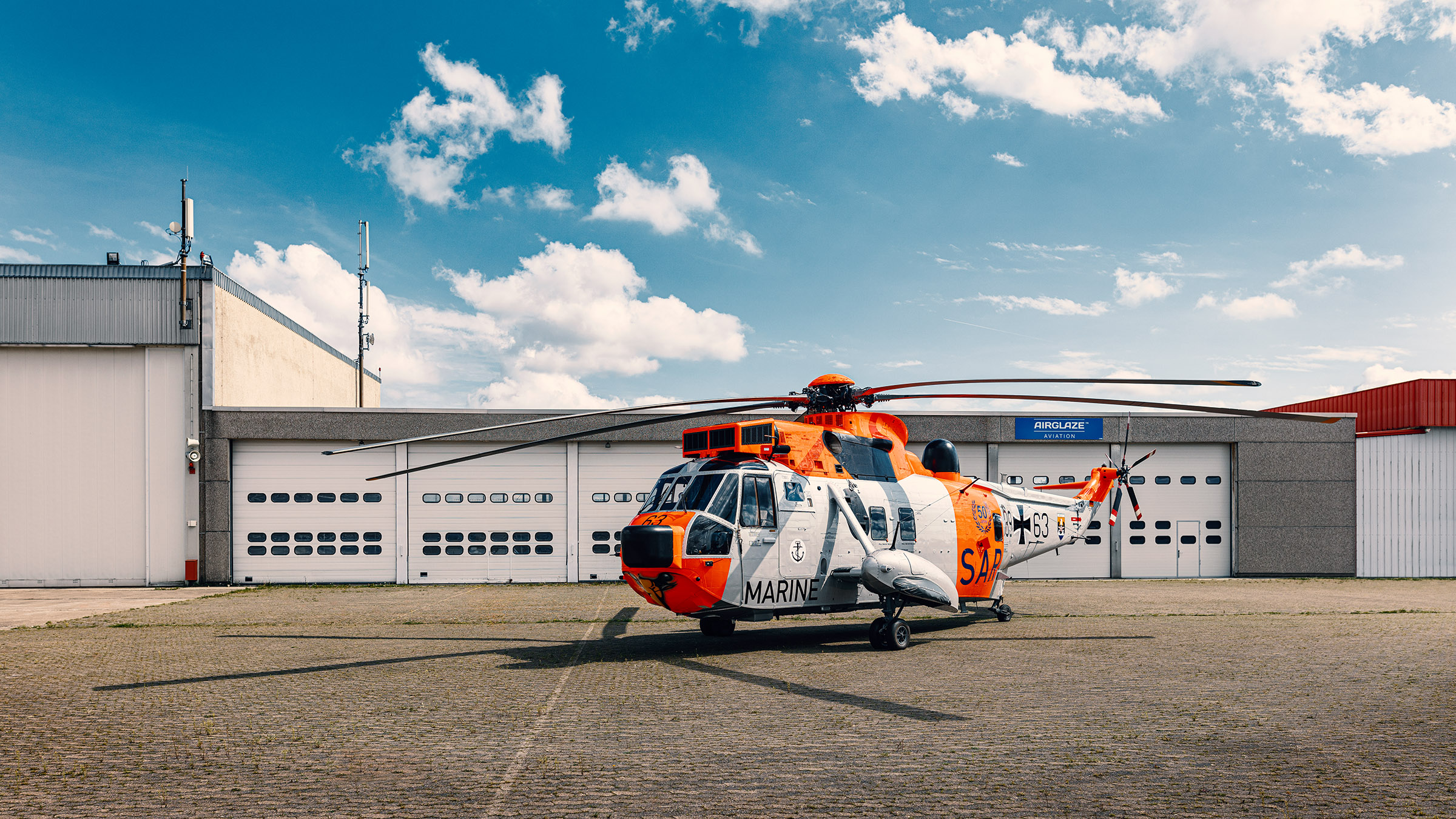 Hubschrauber Sea King vor Hangar mit blauem Himmel