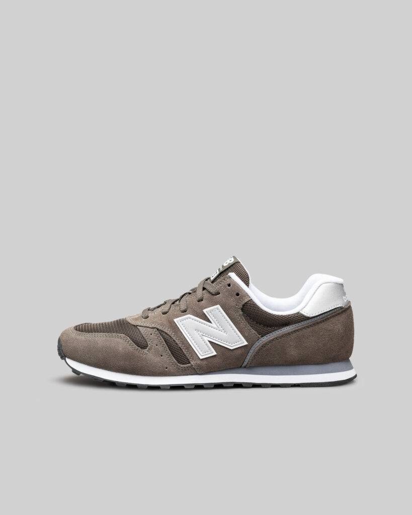 Sneaker linker Schuh Studioaufnahme vor grauem Hintergrund