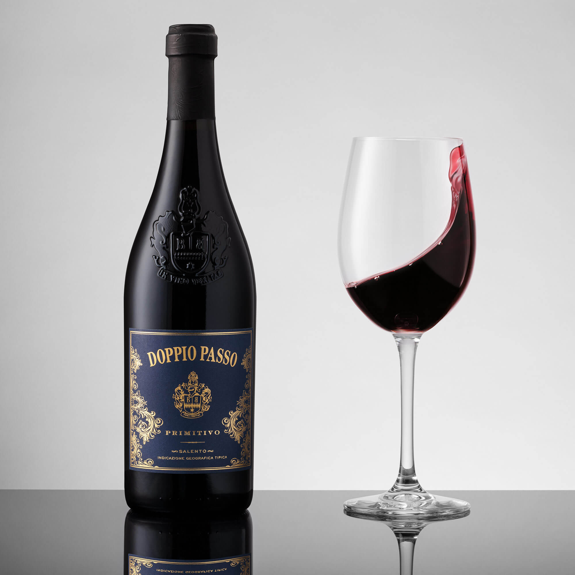 Weinflasche mit Glas vor grauem Hintergrund