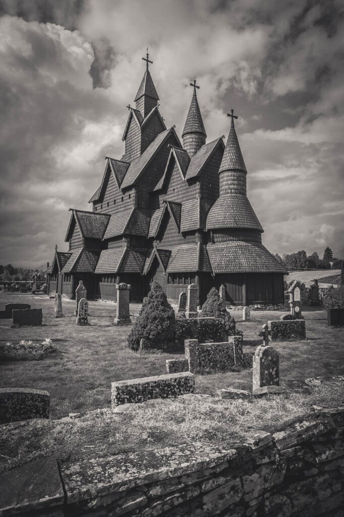 Stabkirche auf Friedhofsgelände mit dramatischem Himmel