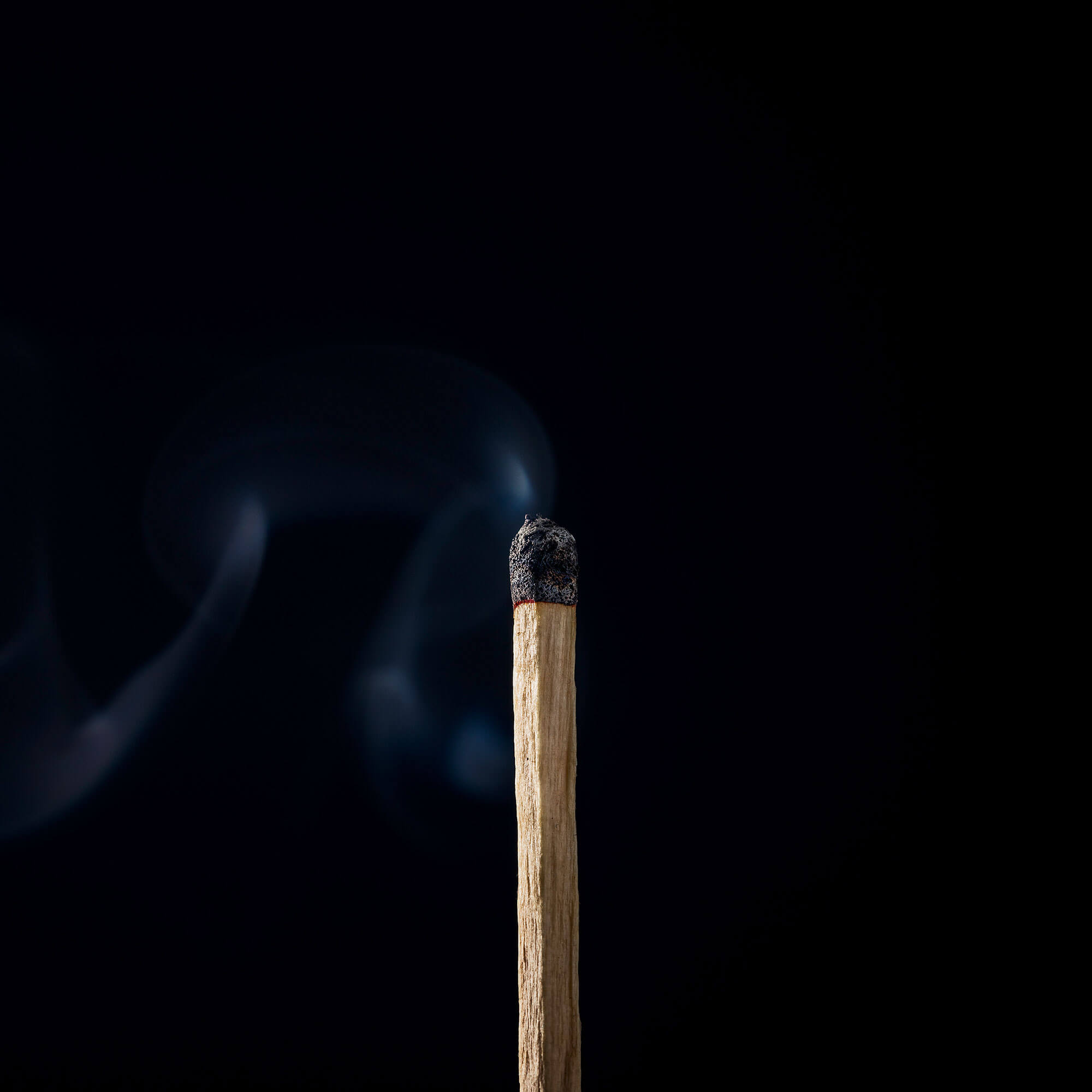 Streichholz mit Rauch vor schwarzem Hintergrund