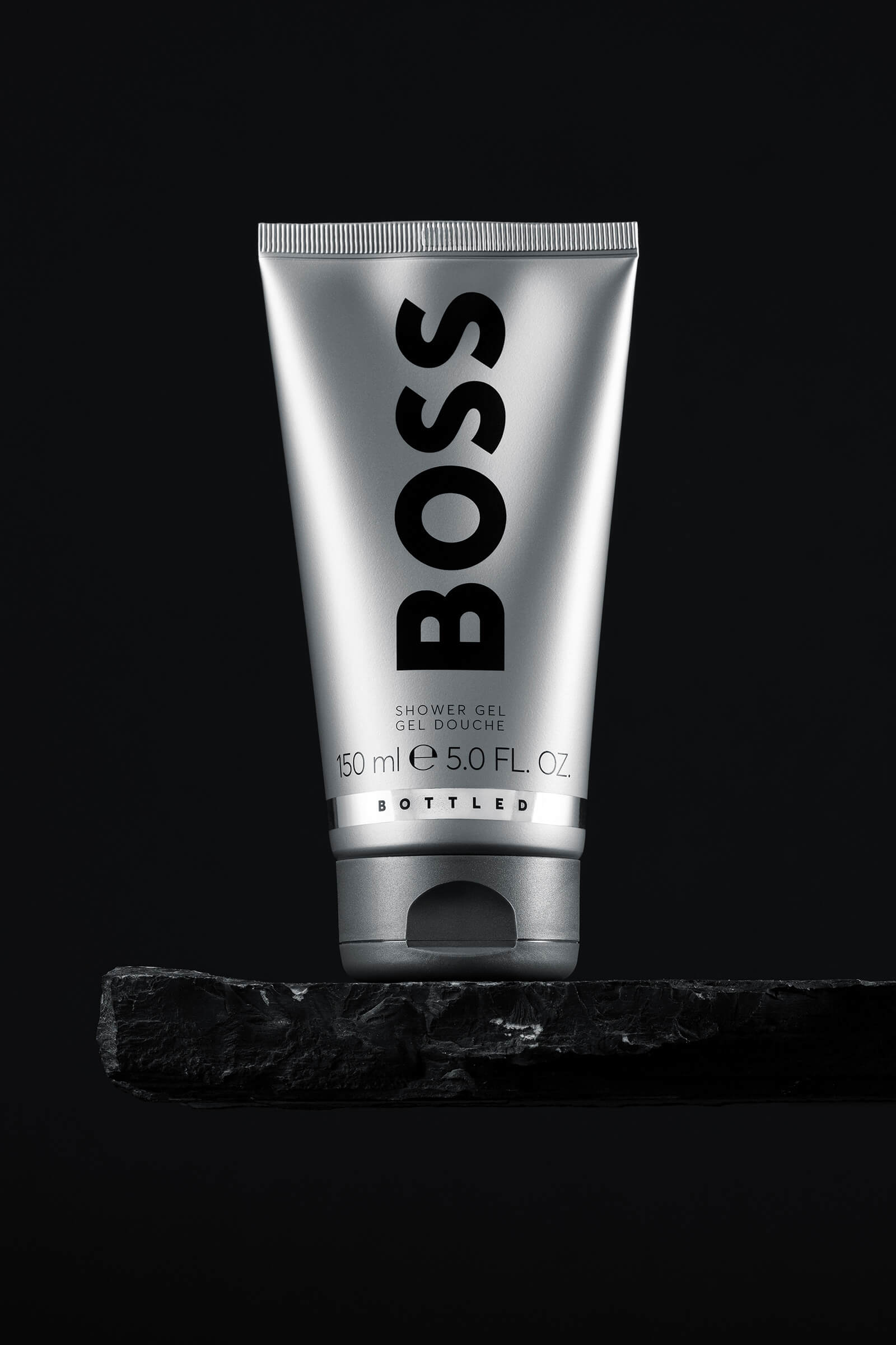 Showergel Hugo Boss auf Steinplatte vor schwarzem Hintergrund