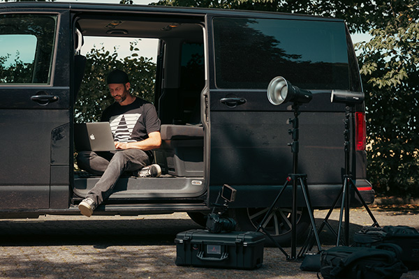 Alex Schmitt sitzt am Laptop in einem VW Bus