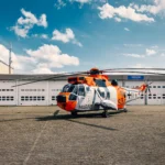 Sea King Hubschrauber auf einem Flugplatz vor einem Gebäude.