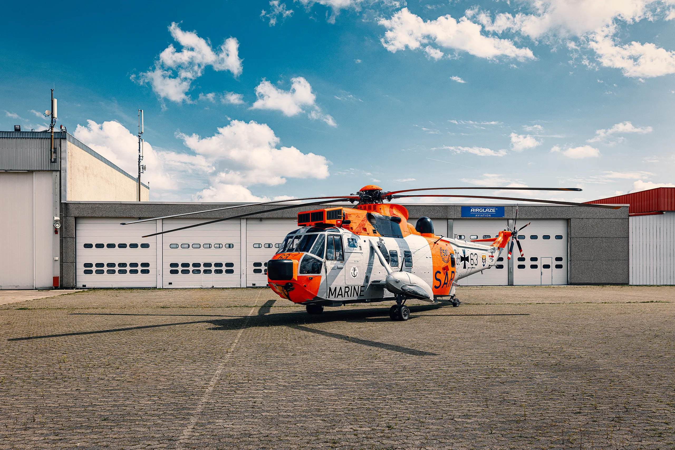 Sea King Hubschrauber auf einem Flugplatz vor einem Gebäude.