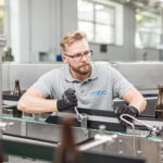 Mitarbeiter bei der Arbeit an einer technischen Maschine in einer modernen Arbeitsumgebung.