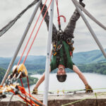 Person beim Klettern in einer Outdoor-Situation mit Seilen und Kletterausrüstung.